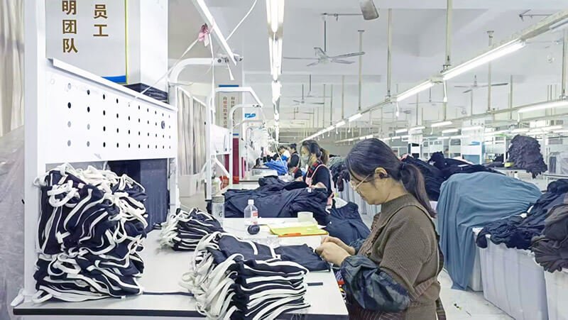 Packaging area workers folding and packing finished activewear for export