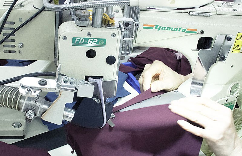 Skilled seamstress sewing activewear on industrial machine